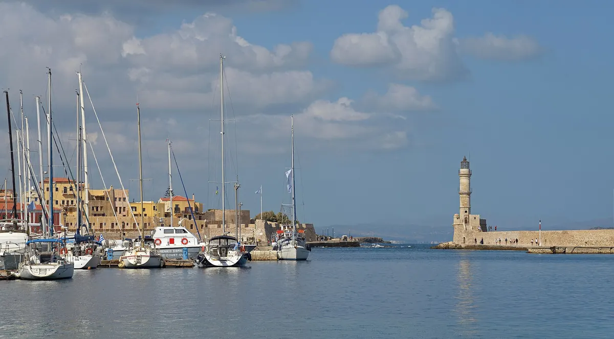 Boats moored in the old Venetian harbor of Chania, Crete, with the waterfront houses behind.