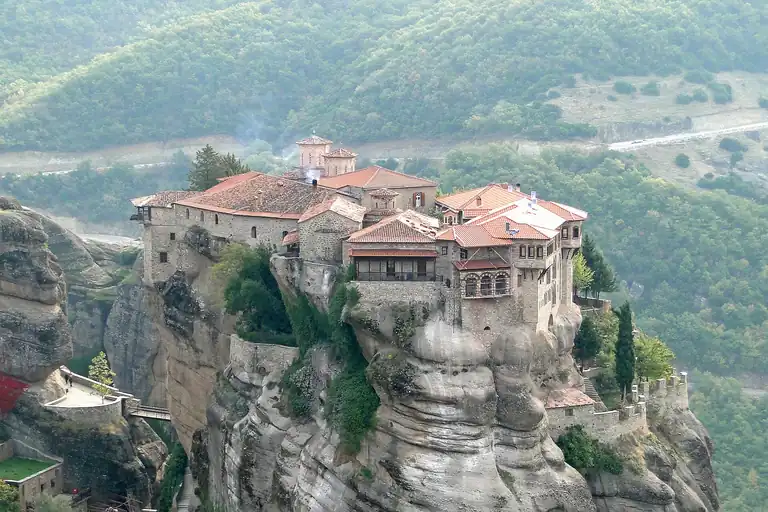 The monastery of Varlaam on its rock pillar at Meteora, with the wooded hills behind it.