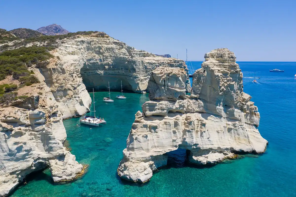 Sailing boats moored among the white rock arches and caves of Kleftiko, on the south coast of Milos.