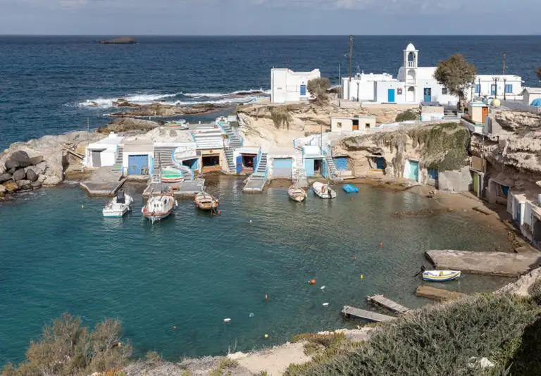 The painted boathouses of Mandrakia on Milos, with fishing boats in the small harbor.