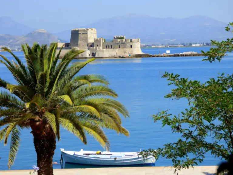 The small fortress of Bourtzi on its islet in the bay of Nafplio, with a palm tree in front.