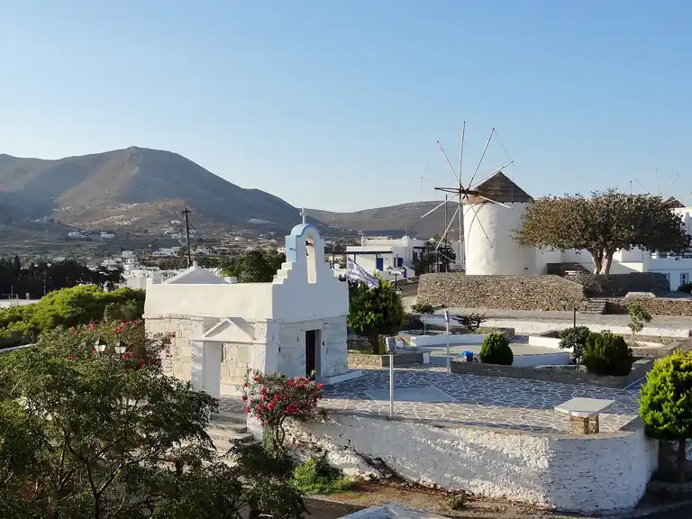 A whitewashed chapel and the windmill above Parikia, Paros, with the hills behind.
