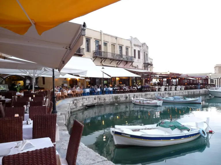 Tables along the Venetian harbor of Rethymno, Crete, with people at dinner in the evening.
