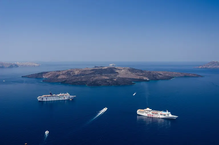 The caldera of Santorini seen from Fira, with the volcanic island of Nea Kameni and ships at anchor.